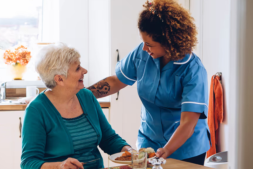 A support worker chatting warmly with an older client