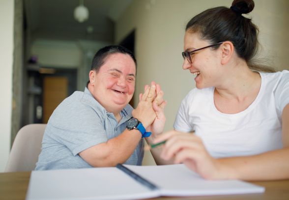 A support worker laughing with a client during a one-to-one session at a table